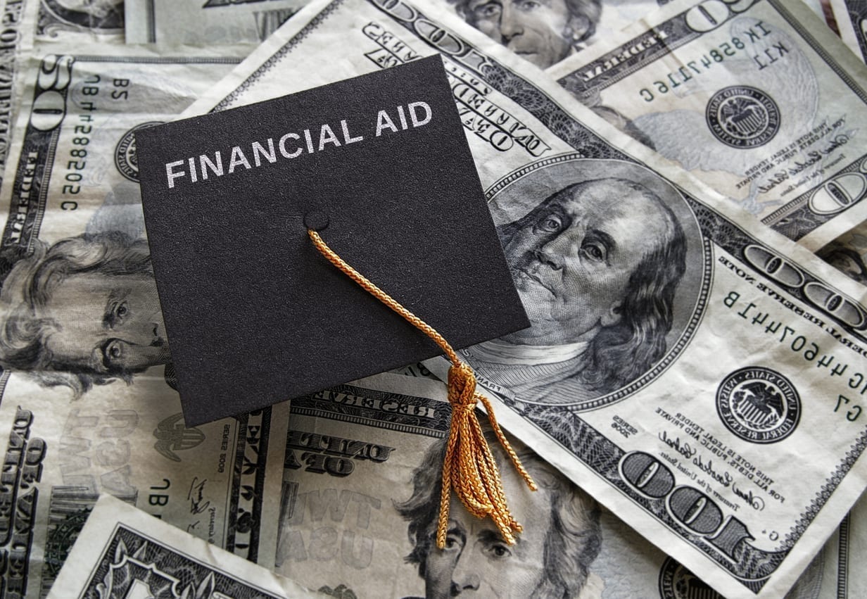 Small graduation cap with Financial Aid text, on assorted cash